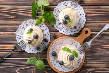 Delicious cupcakes with blueberries on wooden table