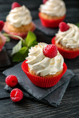 Delicious cupcakes with raspberries on wooden table