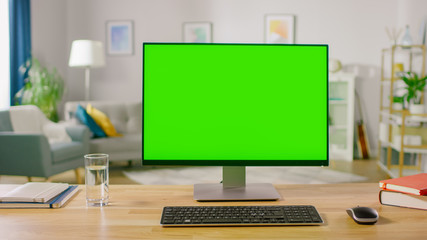 Personal Computer with Mock-up Green Screen Display Standing on the Desk in the Cozy Home Office Living Room of Prominent Designer.