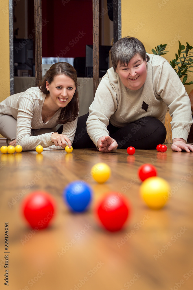 Wall mural Betreuerin und geistig behinderte Frau spielen mit Bällen, Therapie