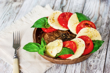 Caprese salad with mozzarella on white wooden background