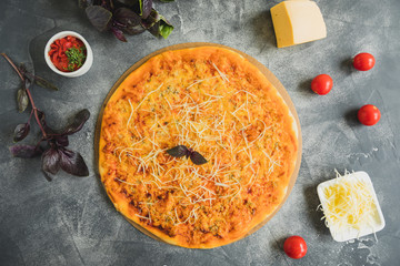 Delicious Italian pizza with bacon, cheese, tomato and basil leaves on dark background. Flat lay,...