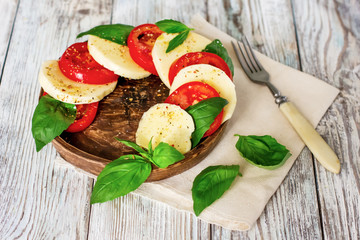 Fototapeta na wymiar Caprese salad with mozzarella on white wooden background