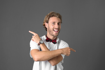 Portrait of handsome man pointing in different directions on grey background