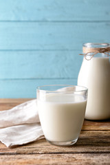 Glass and bottle of milk on wooden background