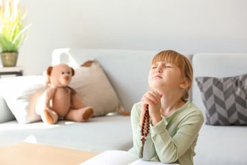 Little girl with beads praying at home