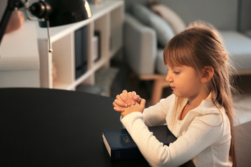 Fototapeta na wymiar Little girl with Bible praying at home