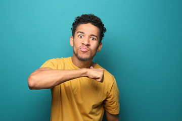 Portrait of aggressive African-American man on color background