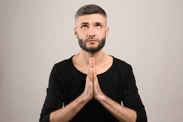 Handsome man praying on grey background