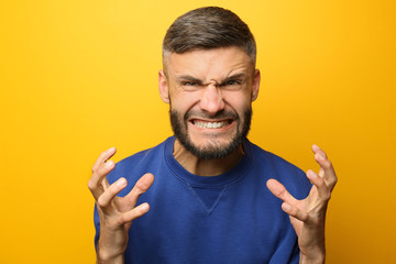 Portrait of aggressive man on color background