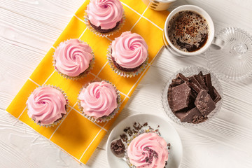 Composition with sweet cupcakes, cup of coffee and chocolate on wooden table