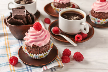 Sweet cupcake with raspberry, chocolate and cup of coffee on wooden table