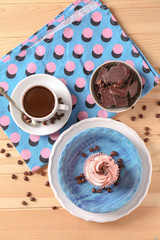 Sweet cupcake with chocolate and cup of coffee on wooden table