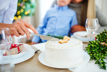 Obraz na płótnie Canvas Unrecognizable woman cutting a cake at Christmas time.