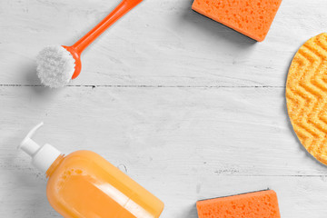 Frame made of cleaning supplies on white wooden background