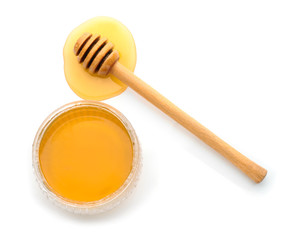 Glass jar with sweet honey and dipper on white background