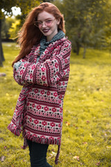 Redhead young happy woman with freckles and dark lipstick wearing sunglasses posing outdoors in park. Looking camera.