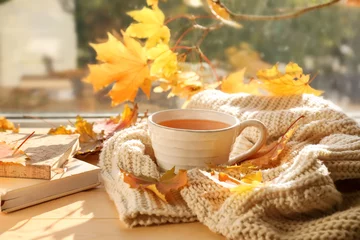 Poster Cup of aromatic tea with warm plaid and autumn leaves on windowsill © Pixel-Shot
