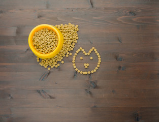 Cat food in bowl and on wood background