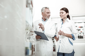 First day. New appealing dark-haired pharmacist listening to her boss attentively while having her...