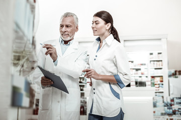 Obraz premium Explaining information. Mature experienced owner of drugstore explaining some information his beautiful employee