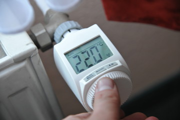 hand dreht an elektronischen vernetzten heizungsthermostat an heizung
