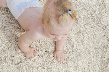 Adorable cheerful baby crawling on the pebble beach