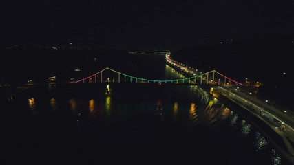 Aerial view from Drone: Top view of the night promenade with bridges and cars. Driving with headlights on the road.