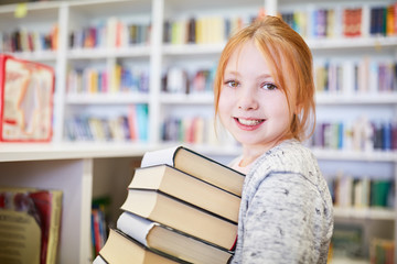 Schülerin mit Bücherstapel zum Ausleihen