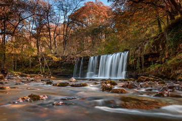 Waterfall Ddwli Uchaf near pontneddfechan in the brecon beacons national park, Wales. It is autumn, and golden leaves are all around.  Long shutter speed for a smooth effect on the water