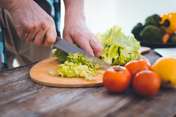 Healthy salad. Close up of lettuce being cut on the cutting board while preparing a salad