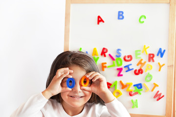 Language education concept. Learn English. Do you speak English. Cute little child girl with colored letters on the blackboard. English language school. English for children.