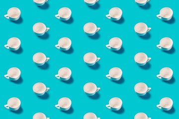 White cups pattern on a blue background flat lay. Top view. Concept.