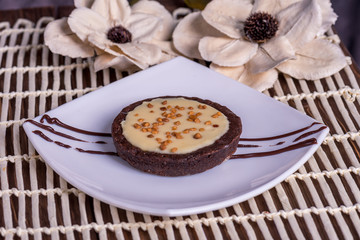 Sweet chocolate brownie with coffe cream on a dark, rustic, wooden table.