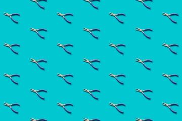 Fototapeta na wymiar Pliers with blue handles pattern on a green background, flat lay. Pop view