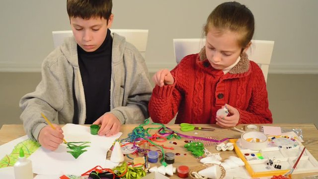 Children making decoration for holidays, crafts and toys, christmas tree and other. Painting watercolors. Top view. Artwork workplace with creative accessories. Flat lay art tools.