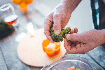 Healthy vegetable. Top view of broccoli being held above the bowl with salad