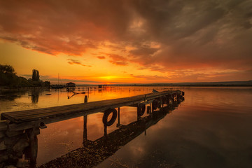 Fototapeta na wymiar Stunning sunset at the seashore at a port with wooden pier