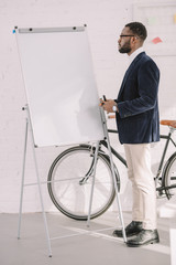 african american businessman working with whiteboard in office with bicycle