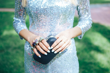 Girl in a silver dress with a small black handbag brass knuckles . Fashion Clothes Accessories Set. brass knuckles 