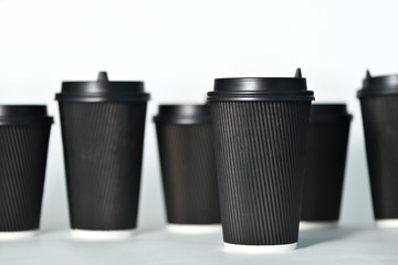 Disposable paper cups in black on a white background. Paper cups for hot coffee. Coffee to go. Paper cup for coffee