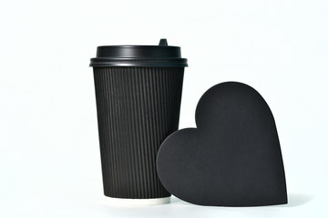 A disposable black paper cup for coffee and a heart-shaped sign. Paper cups for hot coffee. Coffee...