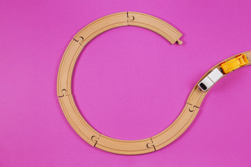 Toy train and wooden rails on purple violet background