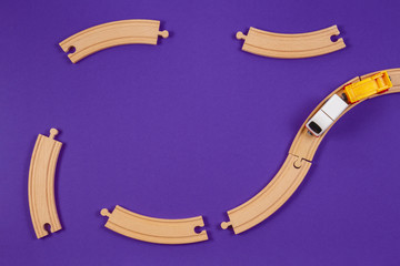 Toy train and wooden rails pieces on blue color background