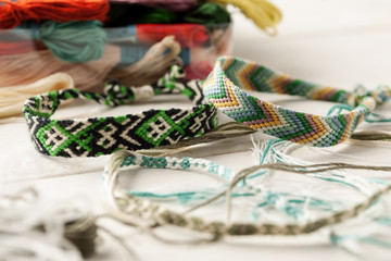 Handcrafted friendship bracelets on a white table with different colored threads