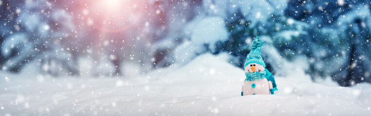 little knitted snowmans on soft snow on blue background