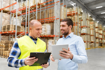 wholesale, logistic business and people concept - warehouse worker and businessman with clipboard and tablet pc computer