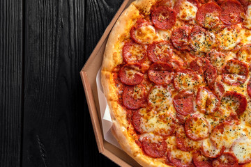 pepperoni pizza on dark black wooden board, top view, place for text, traditional italian pizza