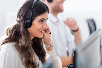 selective focus of smiling female call center operator in office