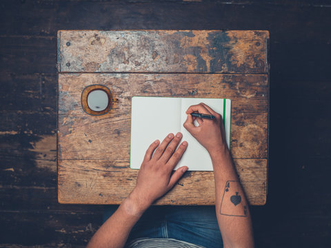 Overhead Shot Of Man Drinking Coffee And Writing Notes